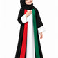 Girl in black Nida open abaya with red and green front bands and white cuffs, hand on heart for UAE National Day